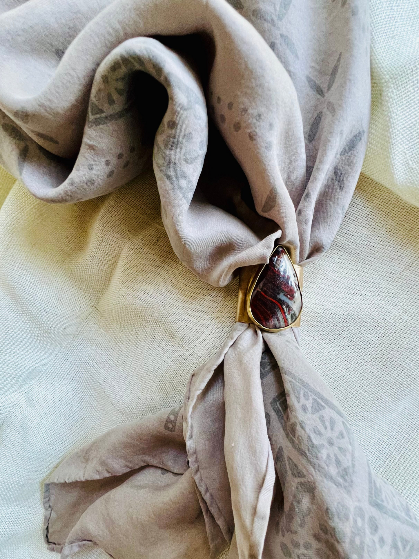 Wild rag bronze bandana slide with snake skin jasper stone. Displayed on silk ozma bandana.
