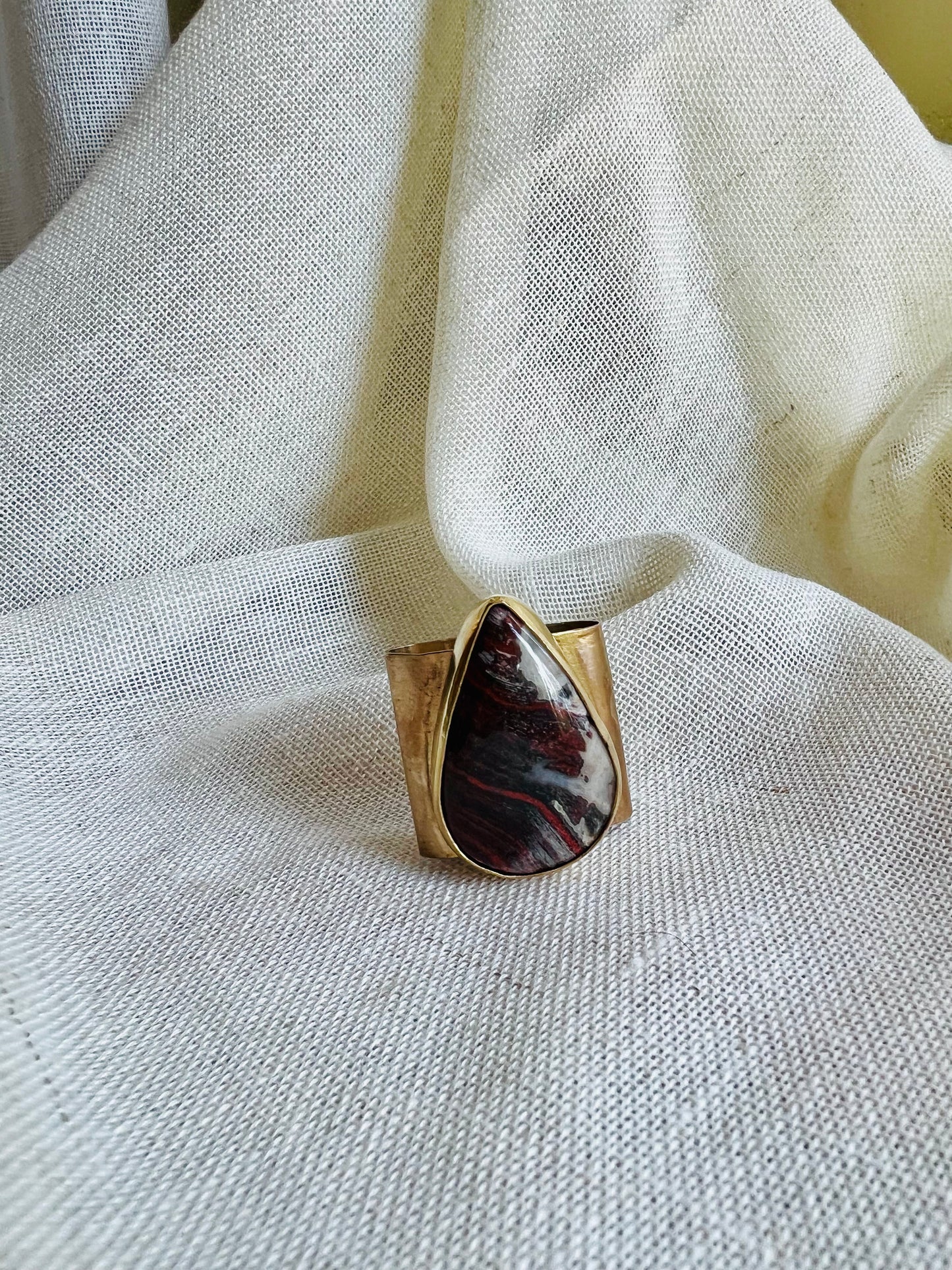 Wild rag bronze bandana slide with snake skin jasper stone. Displayed on cream linen background.