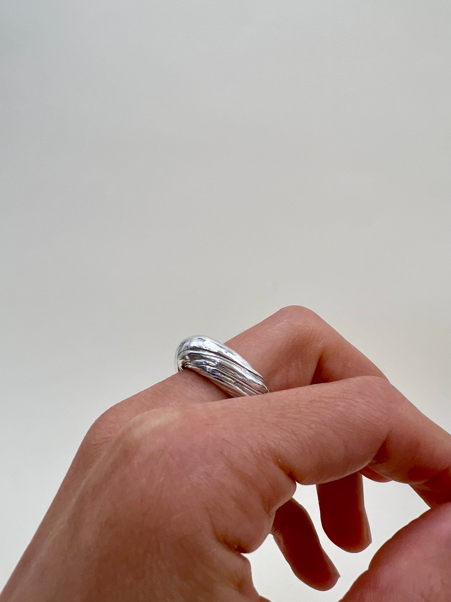 Silver sculptural ring crafted using the Mitsuro Hikime technique by Soul Full Studio. Hand model with white background.