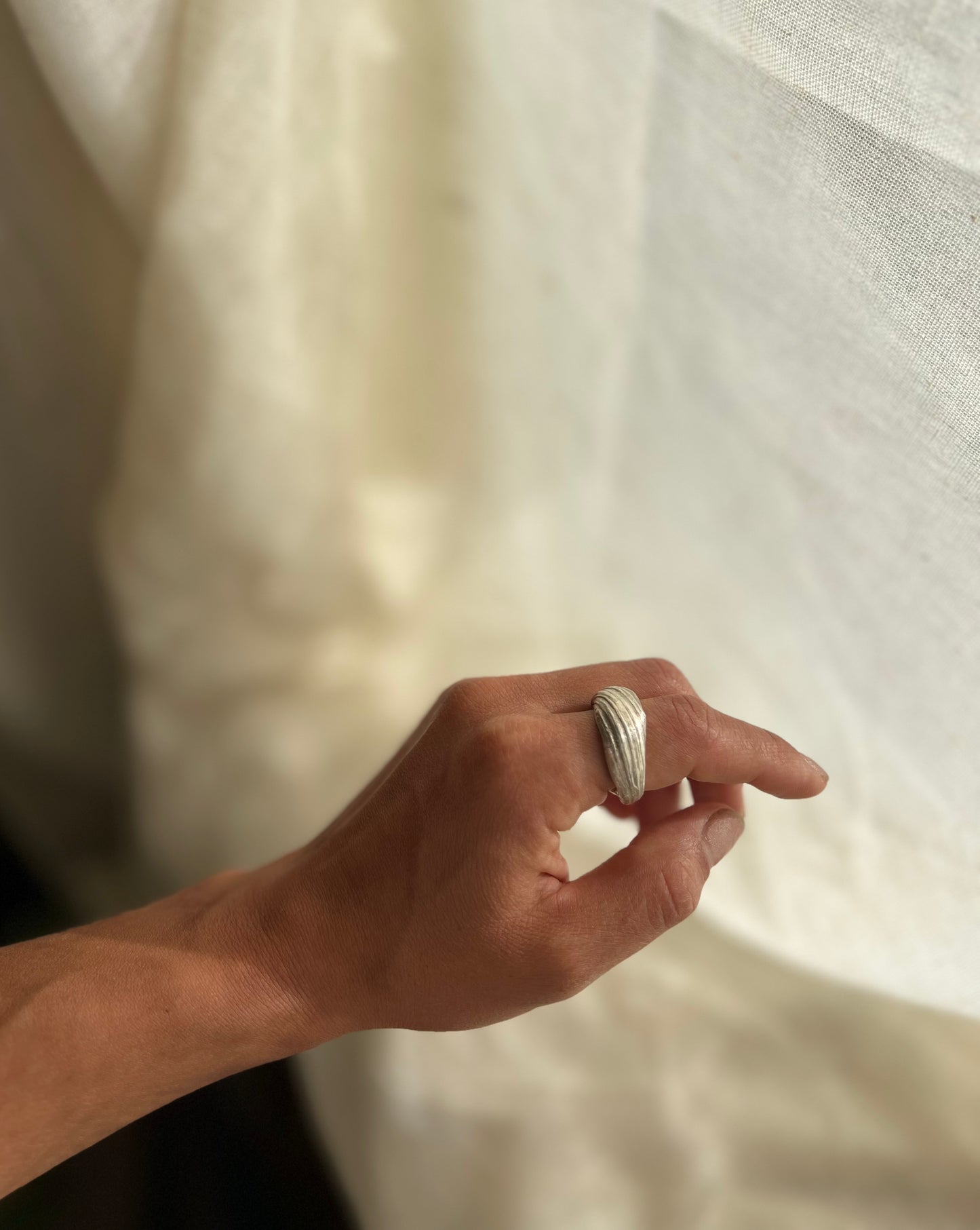 Mitsuro hikime ring on cream linen background. Handmade by Soul Full Studio. Displayed on hand model.