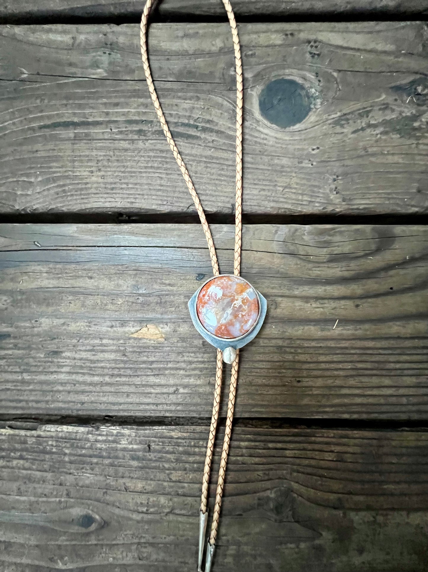 Bolo tie with red moss agate set in sterling silver and tan leather cord. Handmade bolo tie using metal smith techniques.