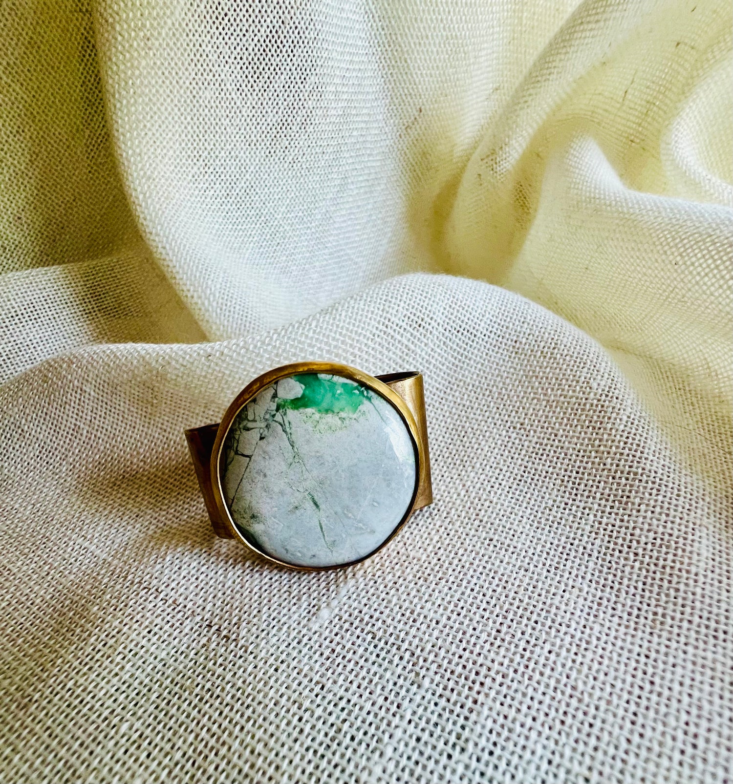 Wild rag bronze bandana slide with green variscite stone. Displayed on cream linen background. 