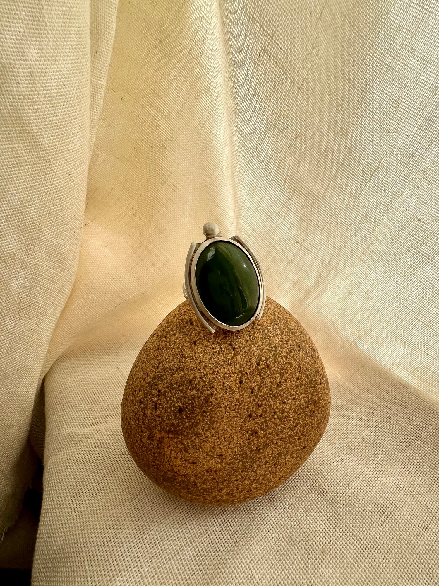 Green chalcedony set in sterling silver. Displayed on rock prop with cream linen background. Handmade from soul full studio using metal smithing techniques. 