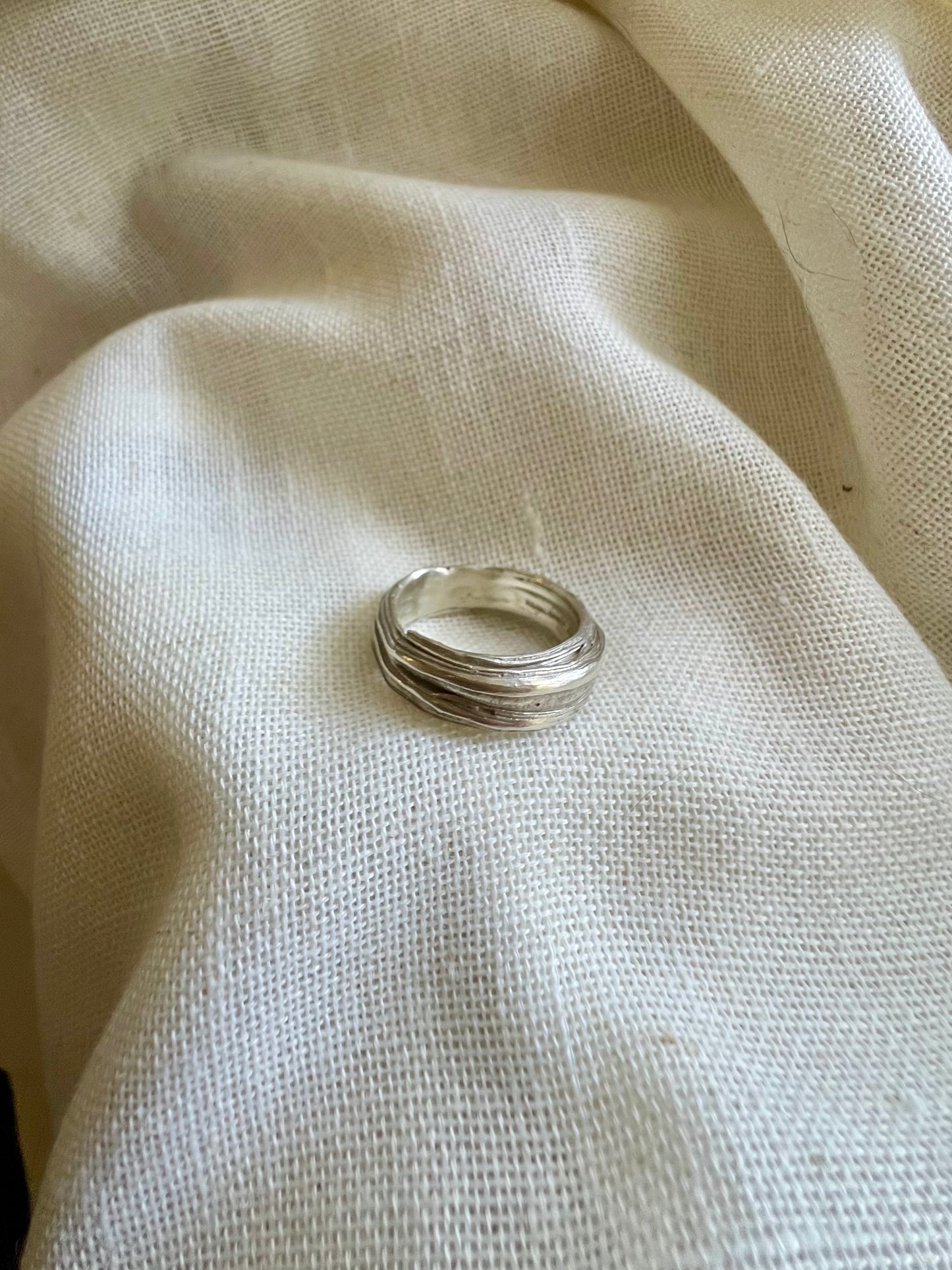 Mitsuro hikime ring on cream linen background. Handmade by Soul Full Studio.