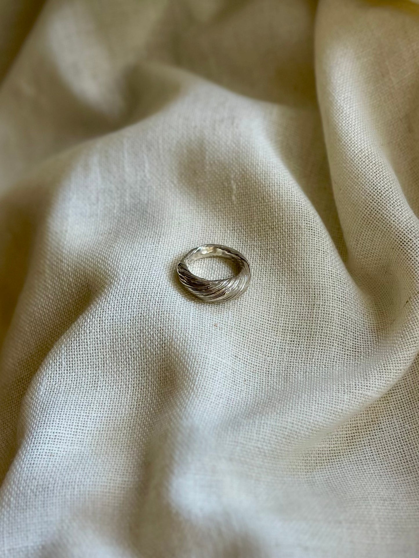 Mitsuro hikime ring on cream linen background. Handmade by Soul Full Studio.