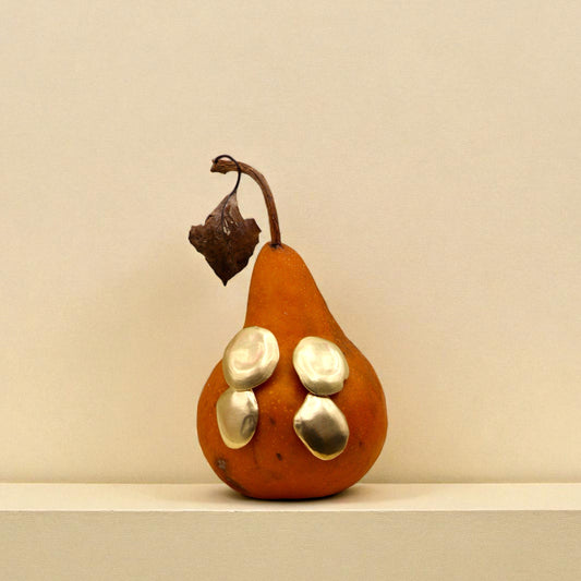 Brass earrings displayed on pear