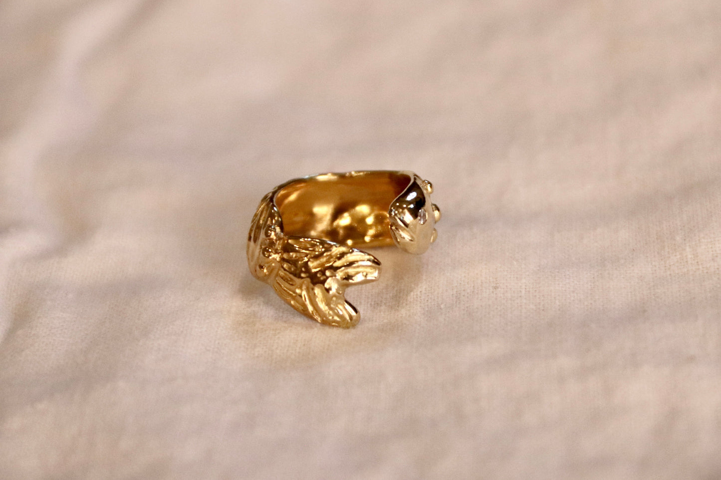 A yellow brass ring shaped like a stylized cream linen background.