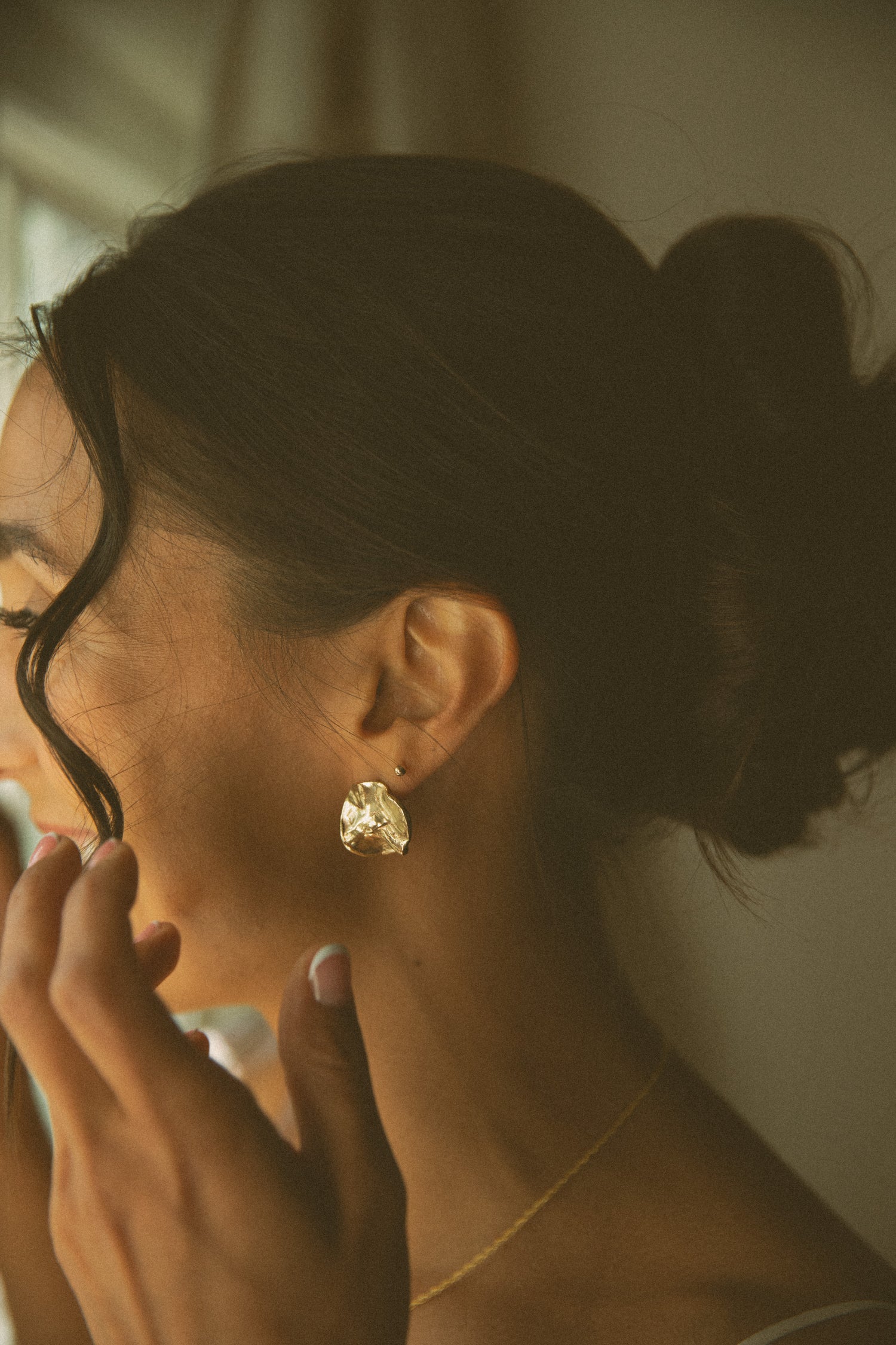 Close-up of a bride wearing a gold earring with a soft focus background