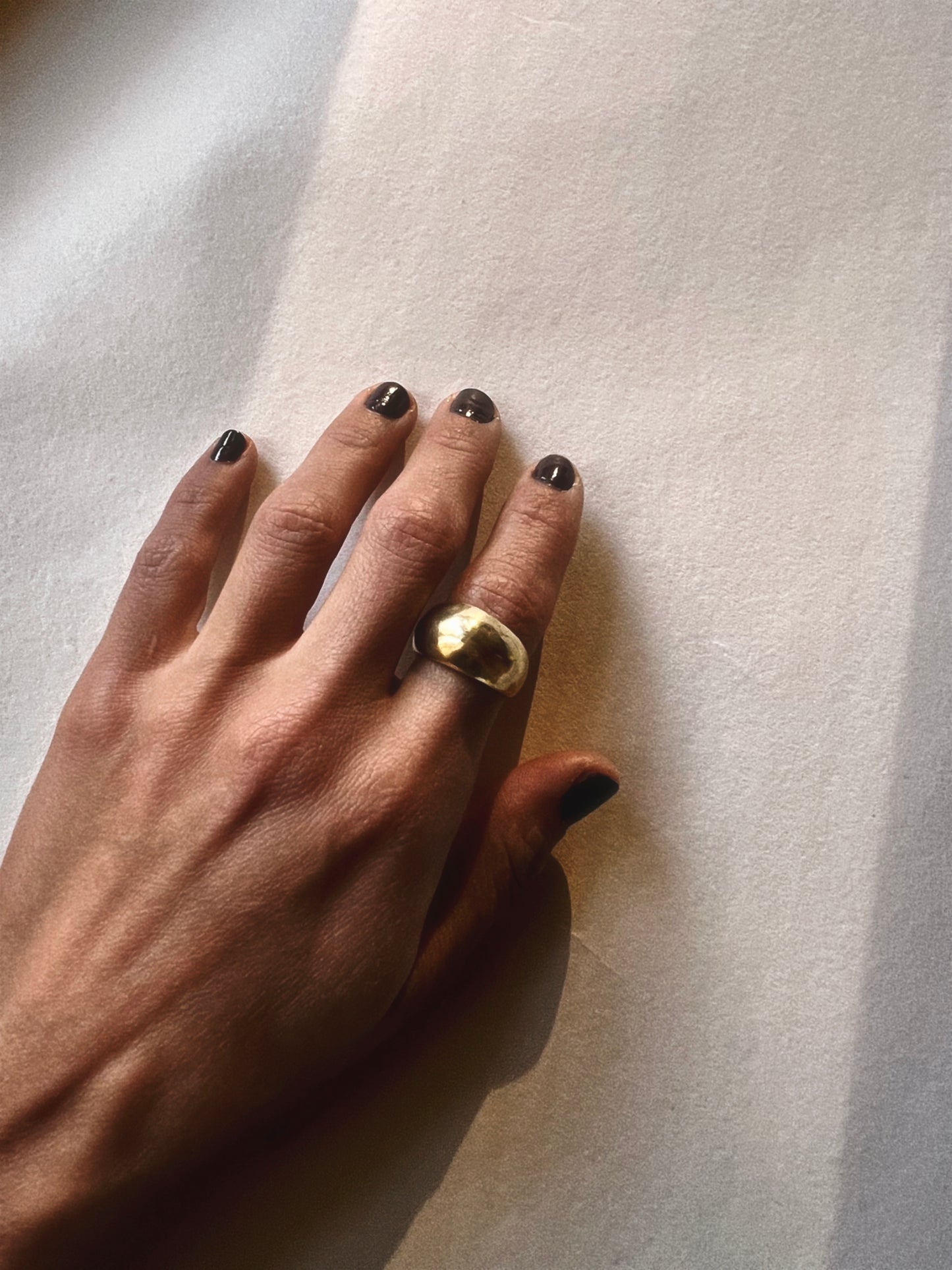 Hand wearing a gold ring on a light background