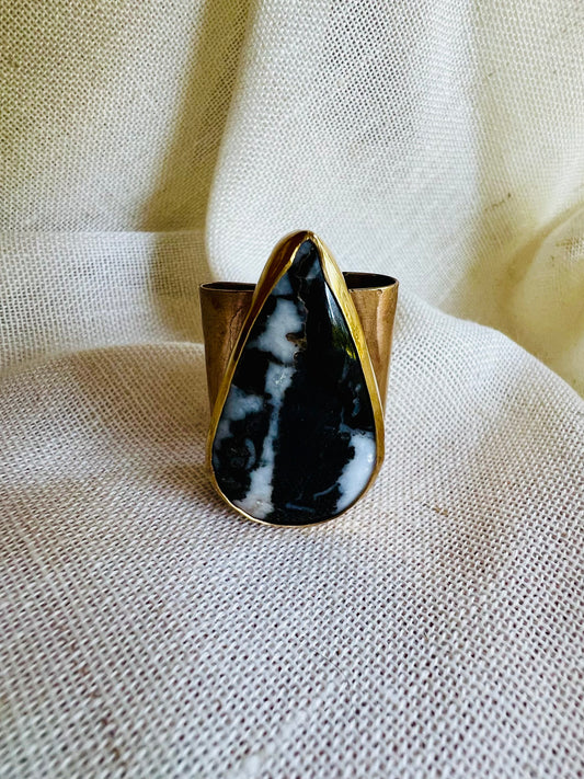 Wild rag brass bandana slide with white buffalo turquoise stone. Displayed on cream linen background. 